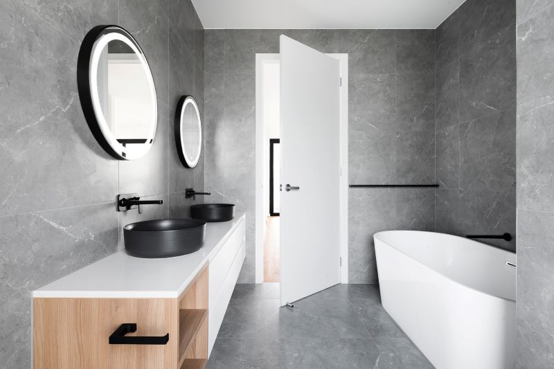 A spacious, well-lit bathroom featuring a tub, two basins, and mirrors.